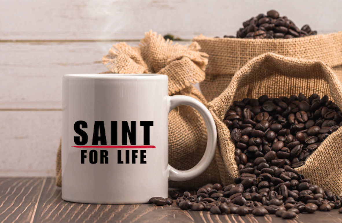 Coffee mug saying Saint For Life with coffee beans in the background